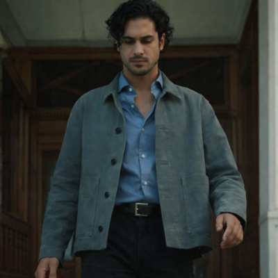 Man wearing a stylish grey jacket over a blue shirt, walking outdoors with a smart casual look